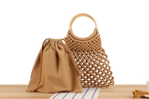 Detail of hand-woven mesh beach bag with round wooden handles and drawstring cotton liner