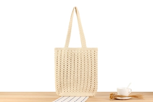Detail of handmade cream crochet tote bag with hollow knit pattern on wooden table