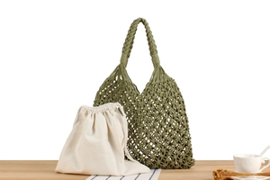 Detail of green handwoven mesh bag with a cream canvas drawstring pouch liner