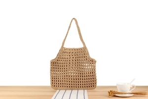 Detailed close-up of khaki crochet hollow mesh knit bag on a wooden table setup