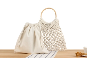 Detail of woven beach bag with round wooden handles and cotton rope mesh texture