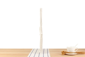 Detail of white cotton woven crochet bag standing on a minimalist wooden table background
