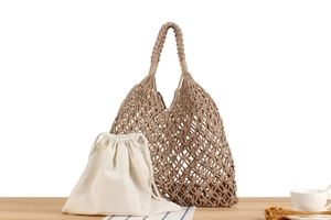 Macro detail of Earth-toned woven hollow bag with cream canvas drawstring inner pouch