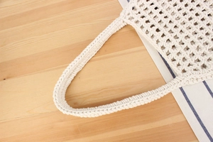 Close-up of beige hollow knit cotton beach bag showing detailed woven mesh craftsmanship