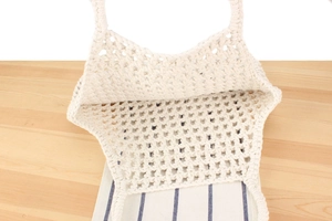 Macro view of beige crochet tote bag showing hollow mesh pattern and cotton weave detail
