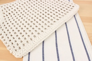 Close-up of beige crochet hollow mesh texture showing intricate hand-woven cotton craftsmanship