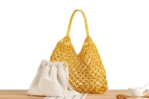 Detail of ginger yellow hand-woven tote bag featuring a removable beige canvas drawstring pouch