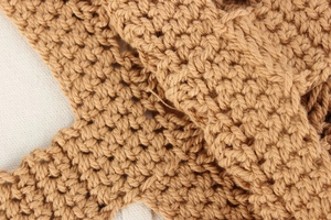Detailed close-up of brown crochet knit texture and hollow pattern on a cotton rope bag