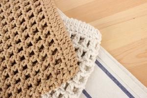 Detail of hollow woven cotton mesh fabric in beige and light brown on wooden surface