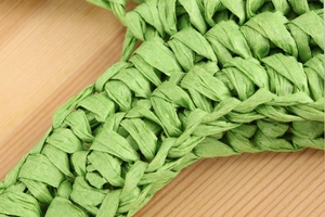 Macro shot of green paper rope woven texture showing detailed handcrafted braid pattern