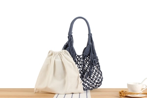 Detail of dark blue handmade woven net bag with a cream cotton drawstring inner pouch