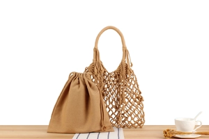 Close-up of woven net shoulder bag with drawstring cotton liner on wood surface