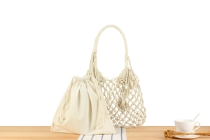 Detail of hand-woven beige cotton mesh beach bag with drawstring liner and tassel detail