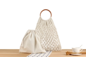 Detail of bohemian cotton rope woven bag with wooden handle and inner drawstring pouch