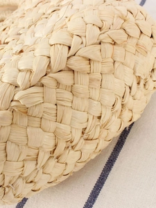 Minimalist handwoven corn husk straw beach bag with a natural textured weave pattern