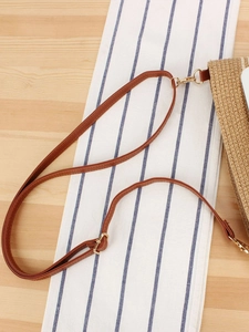 Women's woven straw beach bag with adjustable brown leather shoulder strap and gold metal buckle