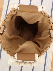 Handmade woven straw bucket bag with wood bead handles and drawstring fabric lining