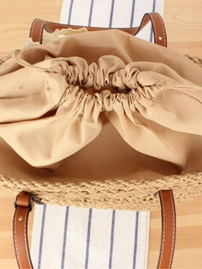 Straw woven tote bag with drawstring lining and brown leather straps for summer vacations
