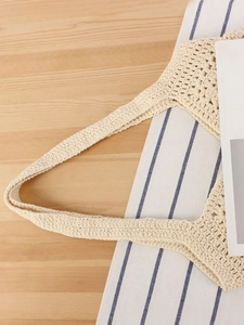 Chic beige crochet knit tote bag with thick straps on a rustic wooden table setting