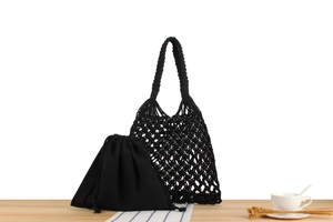 Detail of black hand-woven hollow mesh bag with matching cotton drawstring inner pouch