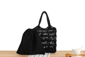 Detail of black macramé woven shoulder bag with removable inner drawstring pouch on wood table