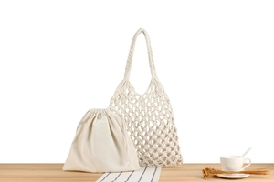 Detail of hand-woven hollow mesh bag with canvas drawstring inner bag on wooden surface