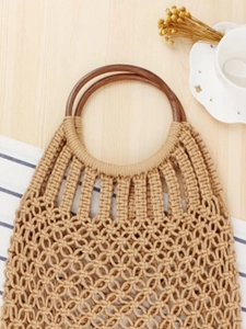Handmade beige woven cotton rope tote bag with round brown wooden handles on wooden desk
