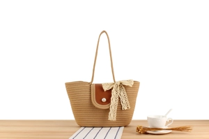 Détail du sac de plage tressé avec rabat en cuir, bouton perle et nœud en dentelle