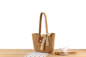 Détail du sac cabas en paille avec rabat en cuir, boucle de perle et nœud en dentelle