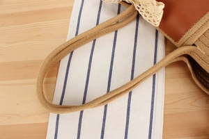 Détail du sac de plage tressé avec nœud en dentelle et garniture en cuir brun