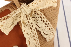 Gros plan d'un sac en paille tressée avec un nœud en dentelle blanche et rabat en cuir