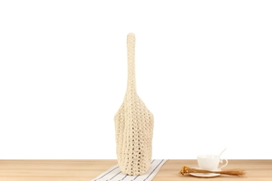 Detail of hand-woven beige crochet tote bag with openwork texture on a wooden surface