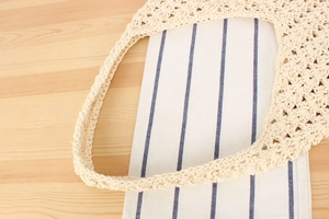 Detail of hand-woven off-white cotton rope bag with intricate hollow crochet pattern