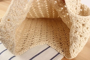 Detailed macro shot of intricate crochet pattern on a beige woven cotton rope handbag