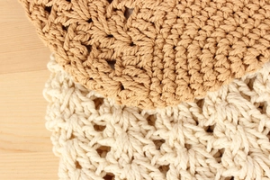 Macro detail of hand-woven cotton crochet texture and hollow patterns on a casual tote bag