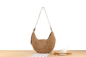 Detail of hand-woven paper rope shoulder bag on casual lifestyle setting with accessories