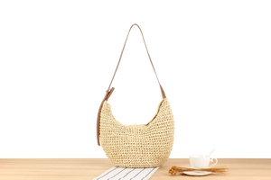 Close-up of minimalist woven paper rope hobo bag with adjustable brown leather strap