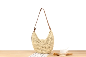 Detailed view of beige paper rope woven hobo bag with adjustable brown leather strap