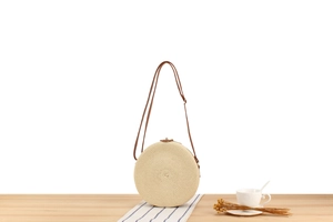 Detail of round woven paper rope crossbody bag with adjustable brown leather shoulder strap