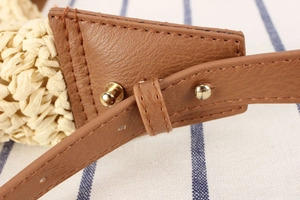 Detail of paper straw weaving with brown leather strap and golden metal rivets