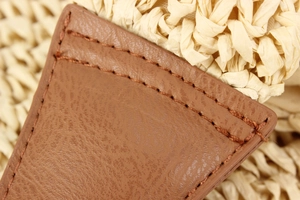 Detail of premium brown leather patch with stitching on ivory woven paper straw bag