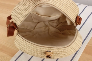 Detail view of woven straw bag interior with lining, side pocket and leather strap