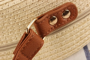 Detail of light beige woven texture and brown leather trim with gold metal rivets