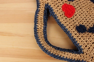 Close-up of hand-woven straw bag with navy blue trim and colorful pom-pom details