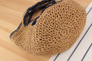 Close-up of hand-woven straw bag with dark blue trim and intricate floral pattern