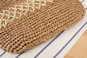 Détail macro du sac en paille tressée avec broderie décorative de motifs à vagues