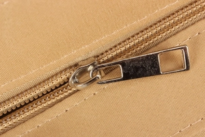 Vue détaillée de la fermeture éclair en métal argenté sur un tissu tissé kaki