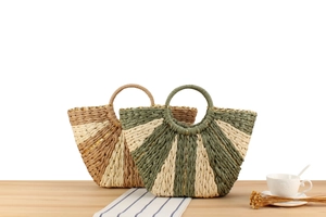 Detail of woven straw handbag with radial texture, gold thread accents on wooden table