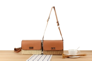Detail view of paper rope woven crossbody bags with leather flap and gold twist-lock