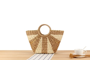 Detail of handmade woven straw tote with fan-shaped pattern and golden thread stitching
